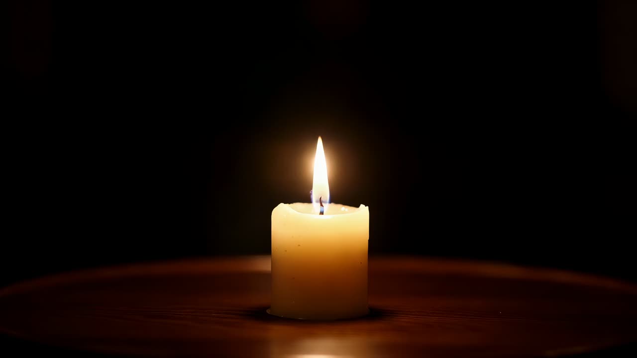 Candela singola color avorio tremolante che si allunga e si consuma su legno scuro lucido, stoppino carbonizzato