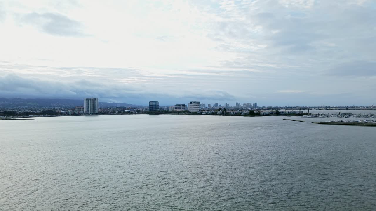 From a distant aerial view, the drone slowly zooms in on Emeryville Marina Park’s waterfront apartments, buildings, and boats.