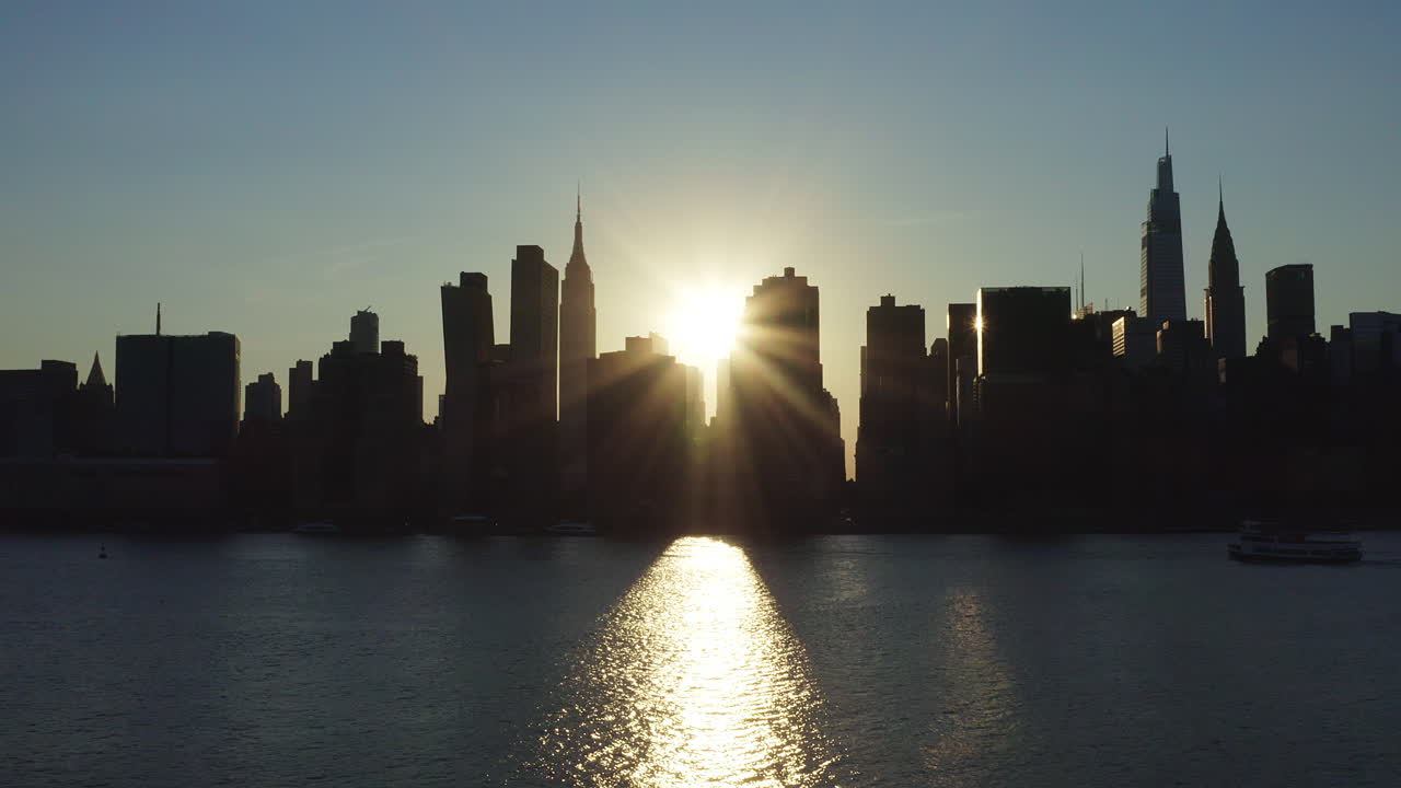 stationary shot at the beginning of the rare Manhattanhenge phenomenon with an intense sunbeam shooting from between the buildings of the legendary skyline