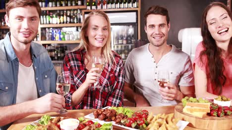 group of smiling friends toasting together during a meal