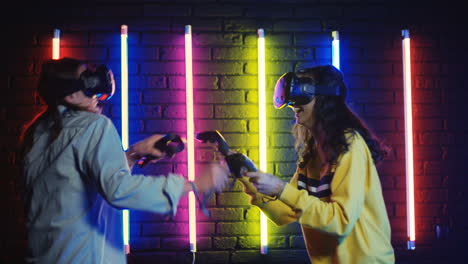 Close-Up-View-Of-Young-Man-And-Woman-In-Vr-Glasses-And-Playing-A-Virtual-Game-In-A-Room-With-Colorful-Neon-Lamps-On-The-Wall-1