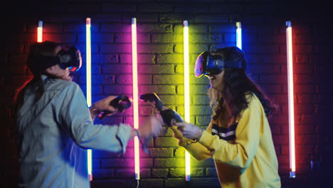 close up view of young man and woman in vr glasses and playing a virtual game in a room with colorful neon lamps on the wall 1