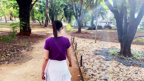 walking behind a fit woman exercising in a city park