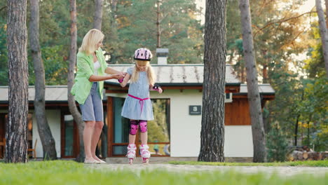 mamá le enseña a su hija a patinar en patines él trata de mantener el equilibrio entrena en el backya