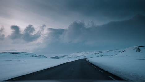 POV-driving-video-through-Northern-Iceland's-snowy-landscape-at-sunset,-capturing-serene-winter-beauty-and-soft-lighting