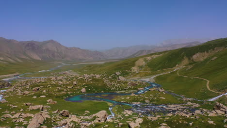 scenic aerial drone view flying over a majestic mountain valley and alpine river in kyrgyzstan