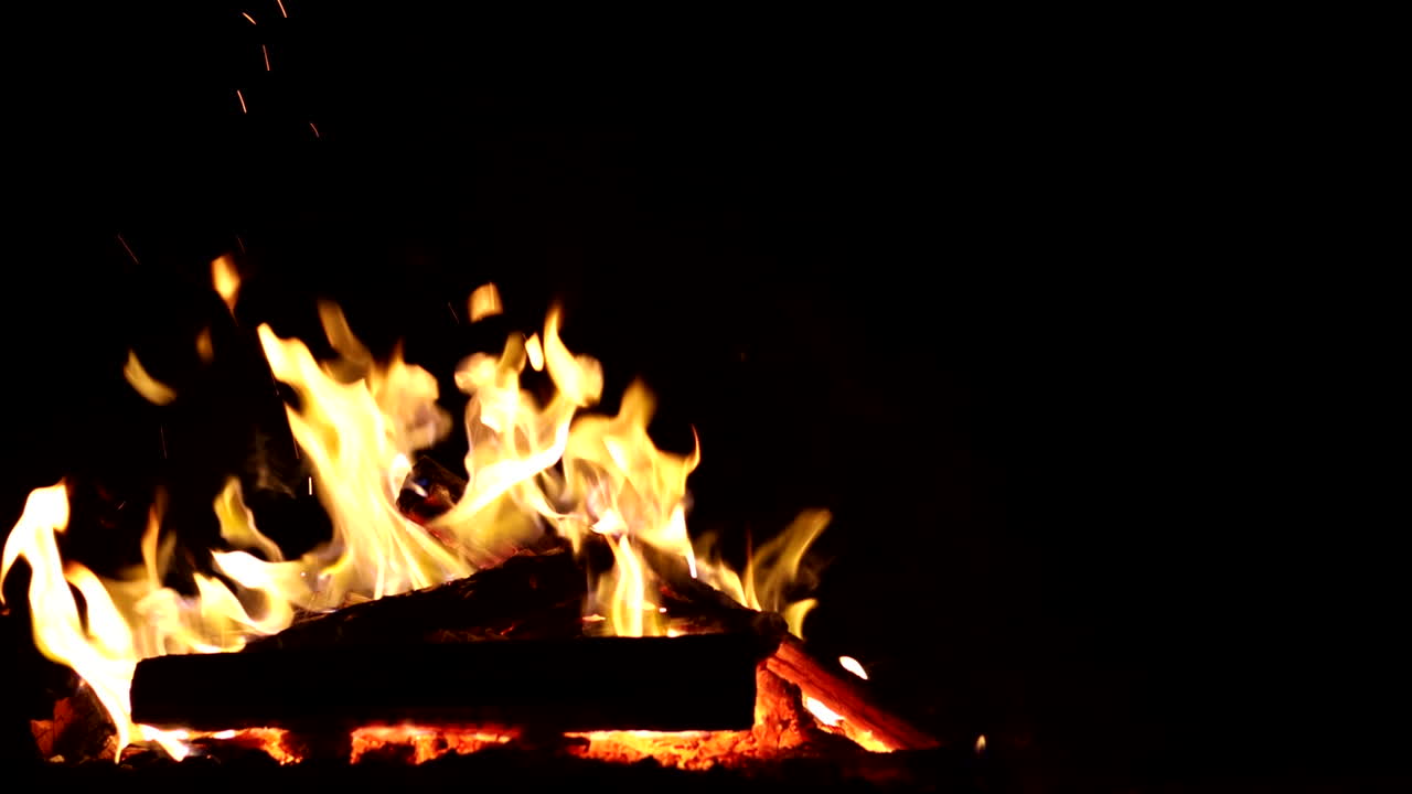 Cozy wood fire at night, crackling with glowing embers, perfect for grilling and food preparing