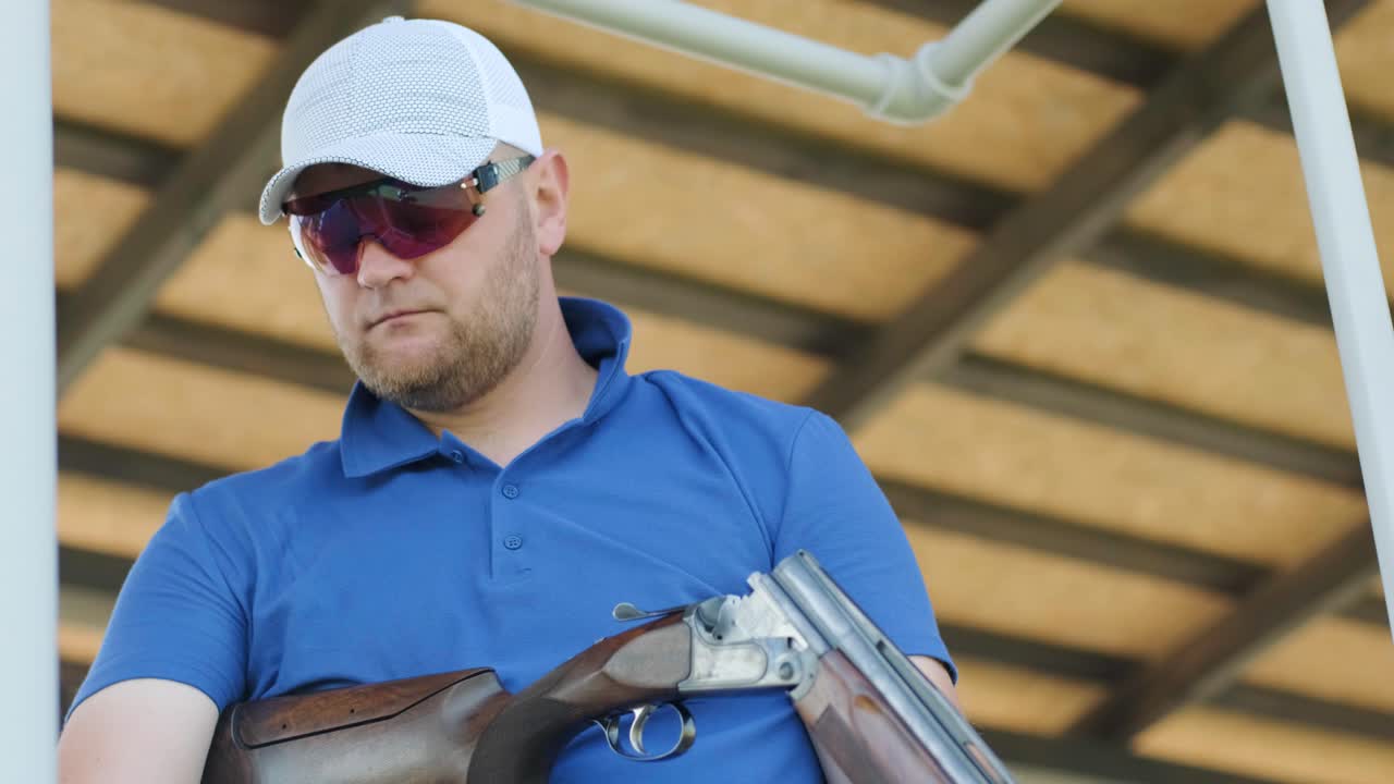 un deportista dispara con una escopeta de doble cañón, un campo deportivo para una prueba de tiro está disparando a un esquete volador