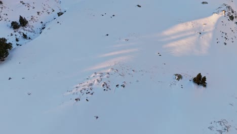 circular top-down drone footage of snow in the mountains with a golden sun in the pyrenees mountains