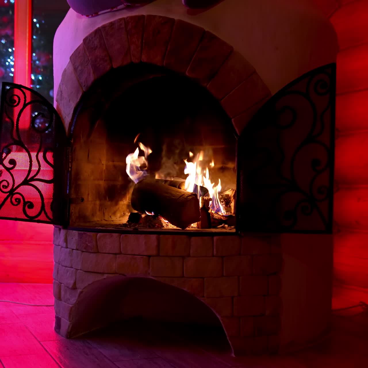 Home hearth in winter. Burning firewood in brick fireplace next to the Christmas tree. Christmas interior background. Warm fireplace at a country house in New year