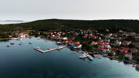 un avión no tripulado se eleva sobre el puerto de la isla de ilovik, croacia, estableciendo impresionantes aguas de verano y la aldea.