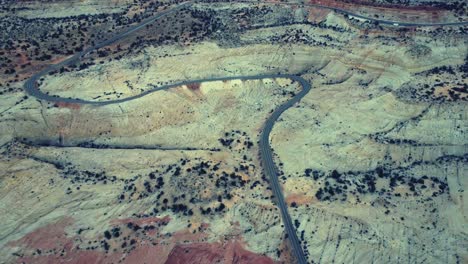 Drone-view-of-asphalt-road-going-through-sandy-valley-in-Utah