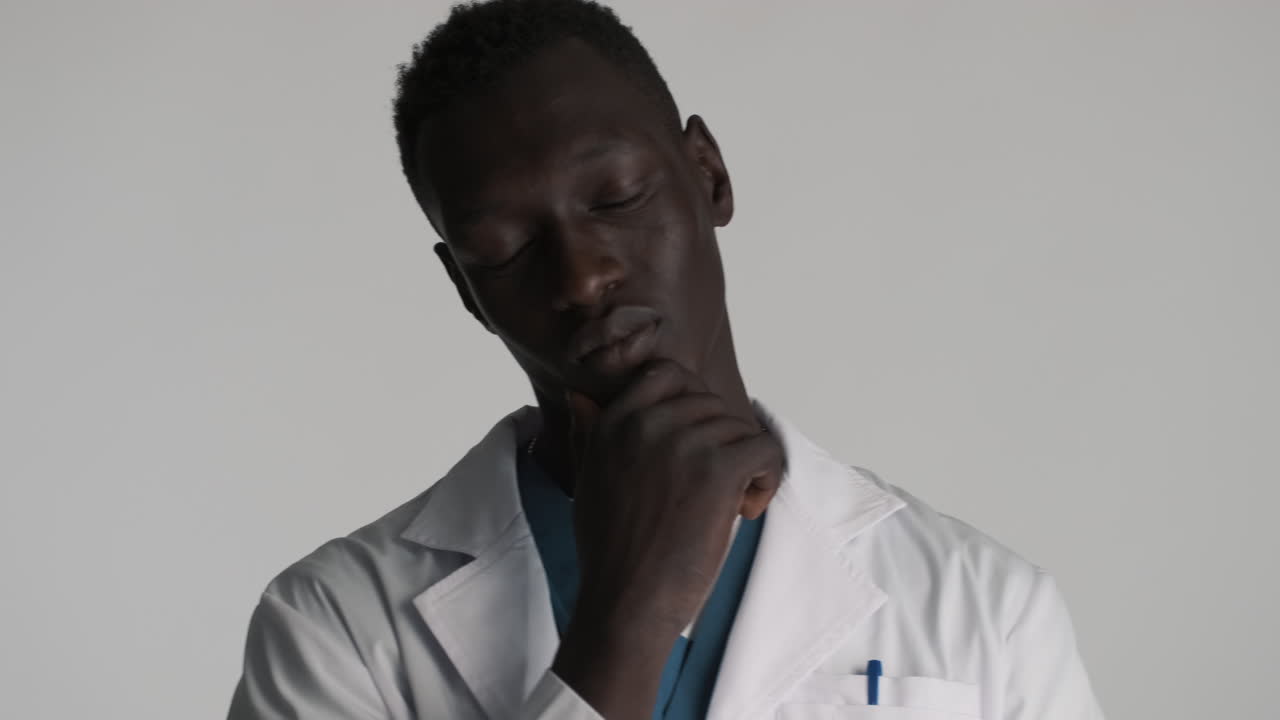 Thoughtful African american doctor on grey background.