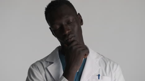 thoughtful african american doctor on grey background.