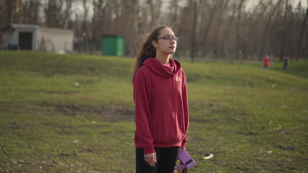 Donna che si prepara con sicurezza per un'attività all'aperto, donna in piedi al parco che tiene un guinzaglio con concentrazione e determinazione, donna che si prepara al parco con l'attrezzatura per il suo cane e un atteggiamento determinato