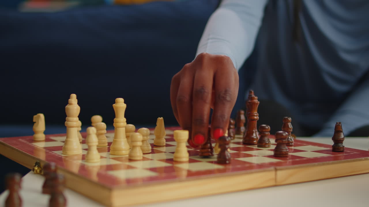 Close up of black woman moving chess pieces on board