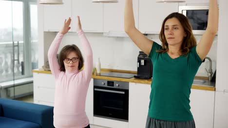 Positive-Reife-Frau-Mit-Behinderter-Tochter,-Die-Zu-Hause-Yoga-Praktiziert