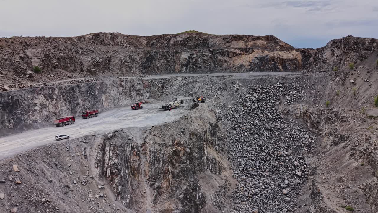 Heavy machinery works in a stone quarry near a river in daytime