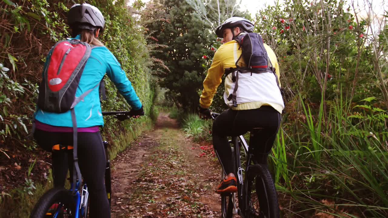 pareja de ciclismo de montaña montando en el bosque en un día soleado