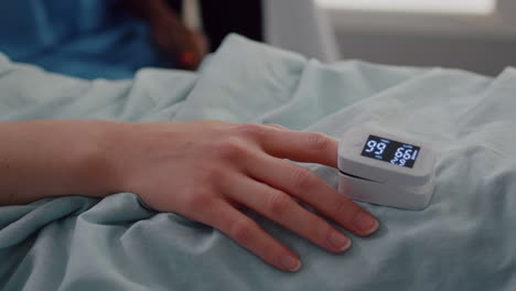 close up of hospitalized woman with finger heart rate monitor showing pulse