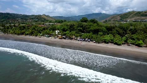 Costa-Rican-Beach-with-waves-and-palm-trees-along-sand