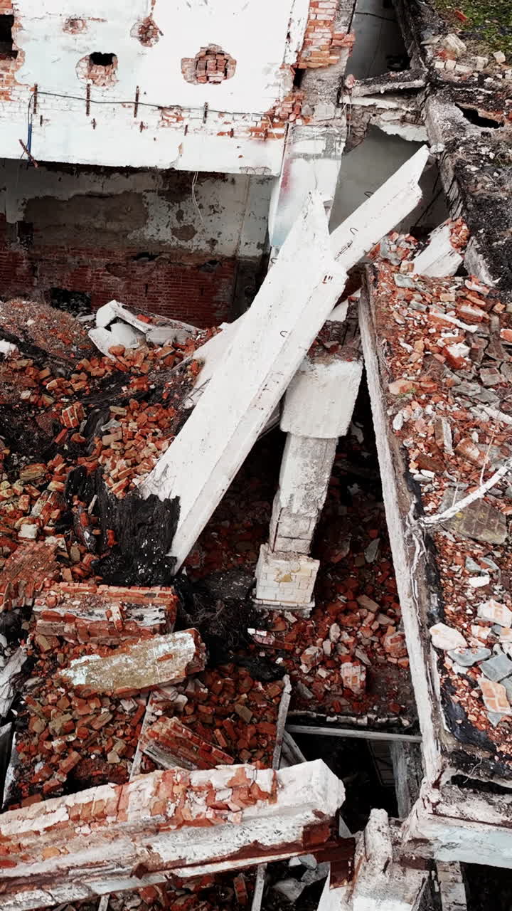 Destroyed architecture after the massive explosion. Enormous hole in the building roof filled with rubbles and debris. Aerial view. Vertical video