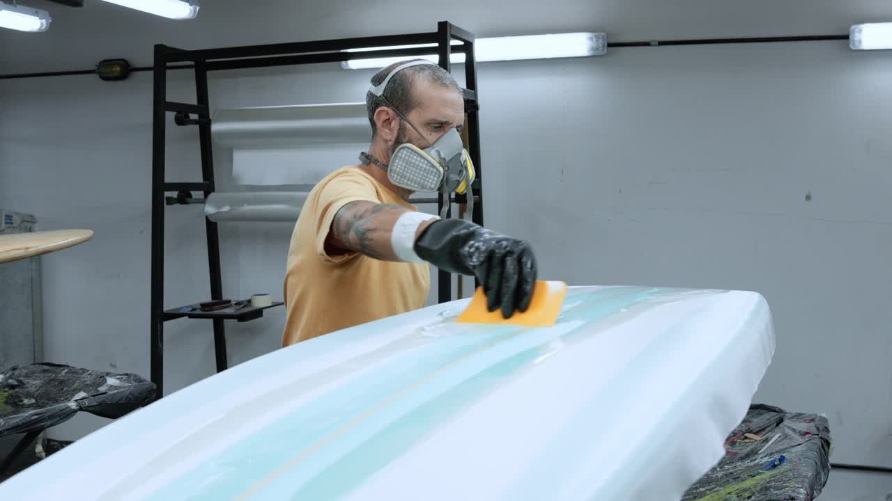 фокусированный человек прикрепляет пленку к доске для серфинга