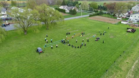 晴れた日にアーミッシュの農地と農園、バレーボールをしているアーミッシュの 10 代の若者のドローン ビュー