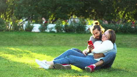 una pareja relajándose en el parque con el teléfono.