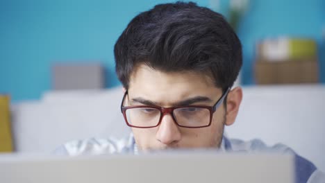 un joven enfocado usando una computadora portátil y regocijándose.