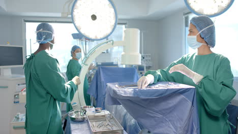 diverse female and male surgeons in masks preparing operating theatre for surgery, slow motion