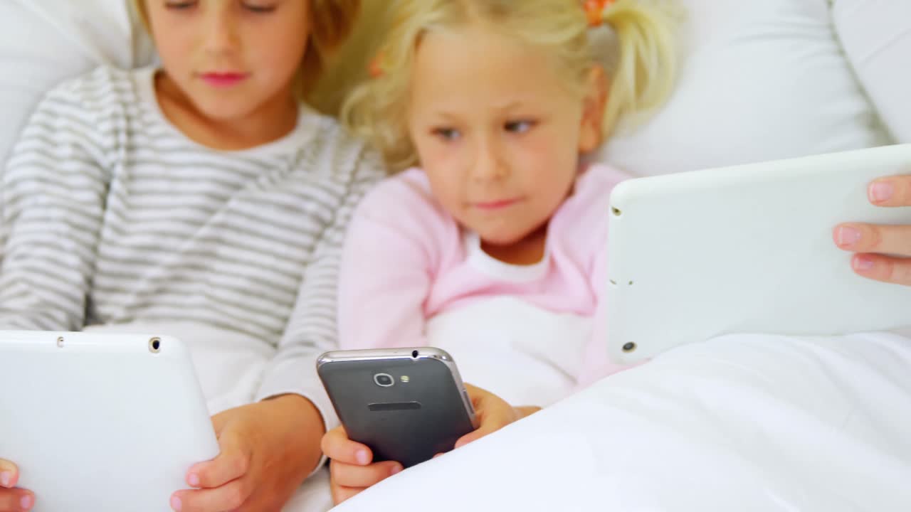 아이들과 엄마는 침실 4k에서 디지털 태블릿과 휴대 전화를 사용합니다.