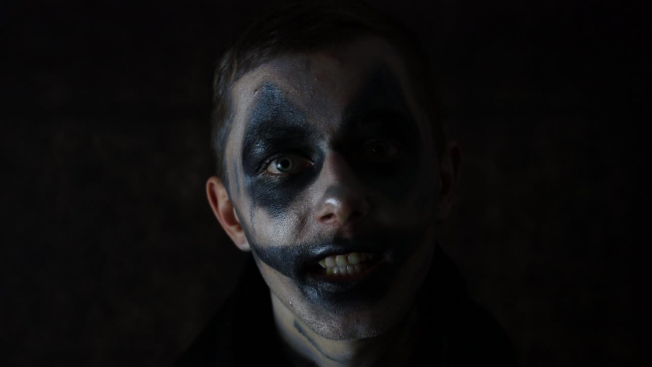 Halloween makeup Caucasian man talking scary performance in front of a black background dark clown
