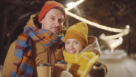 couple kissing and posing against outdoor christmas lights