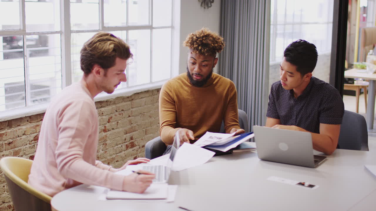Young male creative business team working together in an office meeting room, close up
