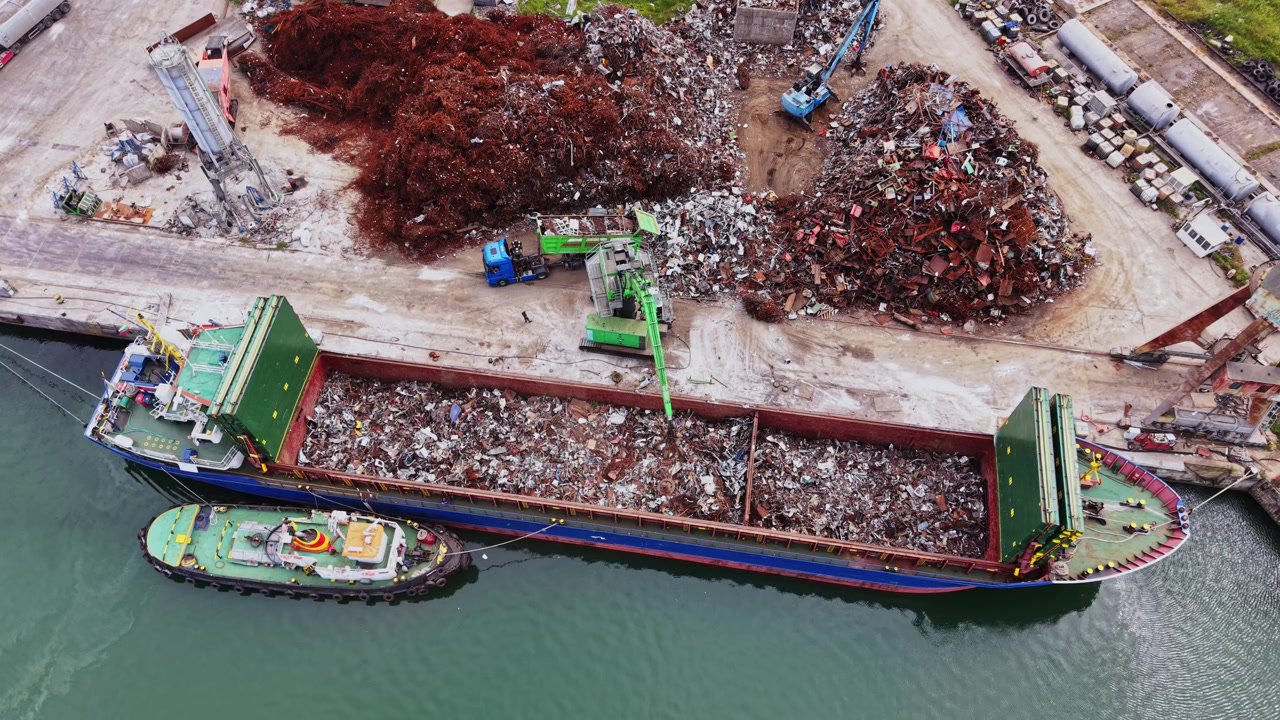 Nave che movimenta rottami metallici in un porto durante le ore diurne