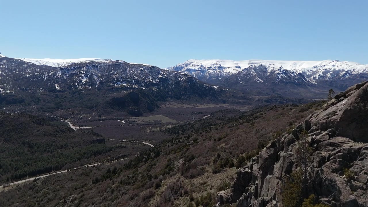 Sorvolo con drone su scogliere montane, bellissima valle con strada, montagne innevate del Cerro Falkner, Neuquén, Argentina
