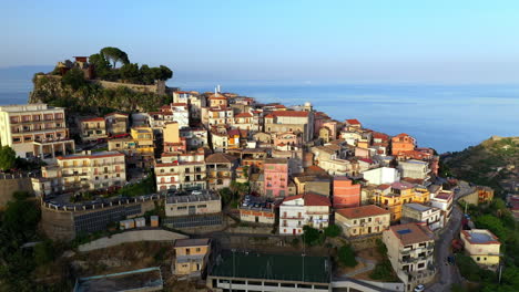 Disparo-De-Un-Dron-Sobrevolando-Casas-Y-Edificios-De-Castellmola-Construidos-En-Una-Terraza-Natural-En-Sicilia,-Italia