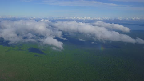 una perspectiva aérea de nubes flotando sobre un paisaje costero verde durante el día