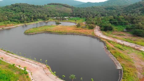 flyaway-drone-shot-birds-eye-view-transmission-tower-power-grid-power-line-by-the-lake-over-the-mountain-jungle