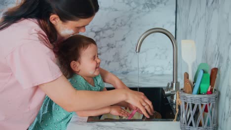 a heartwarming moment of bonding: a mother and daughter playfully wash dishes together in the kitchen, creating joyful memories amidst soap bubbles and laughter