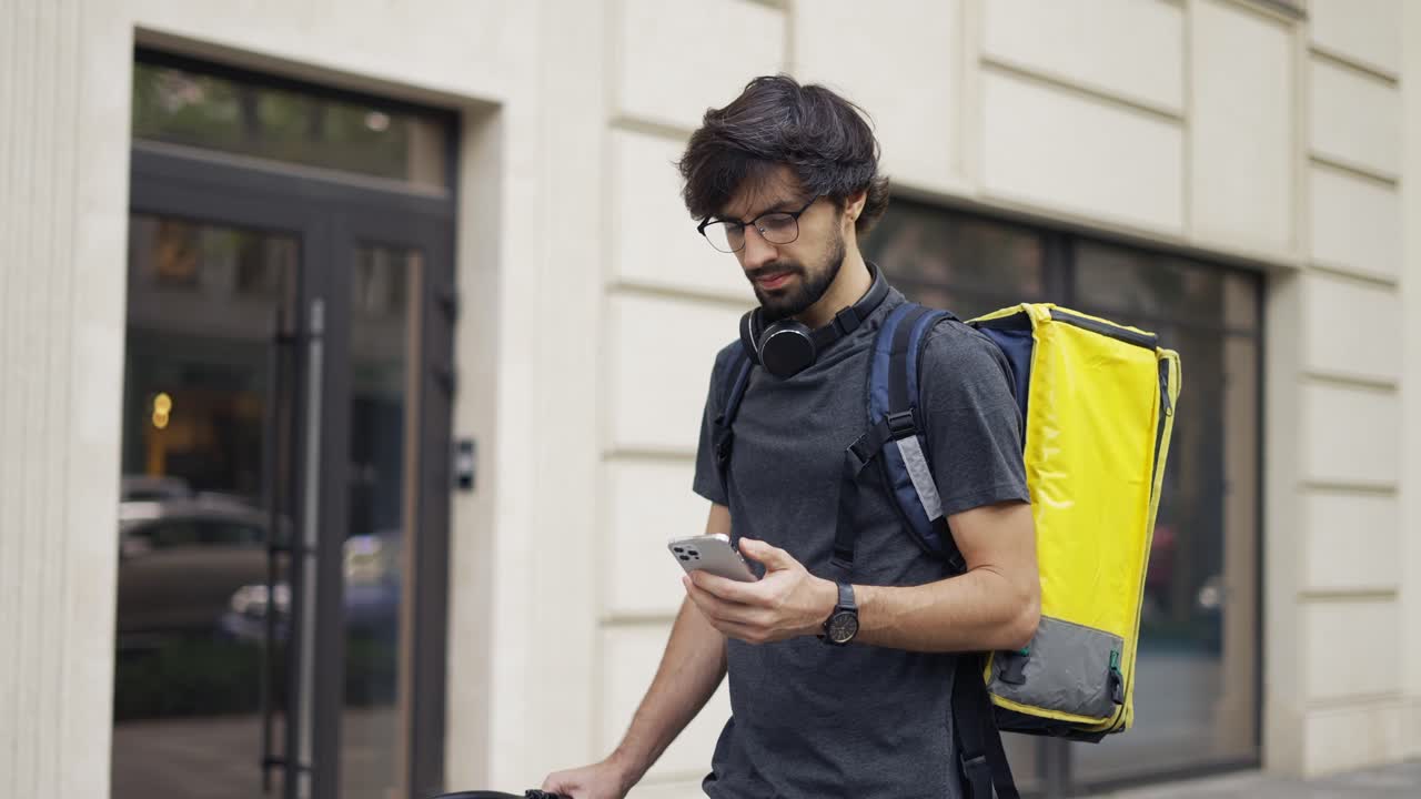Delivery man who is going and looking to the smartphone
