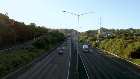 una amplia toma de mano de una carretera ocupada con vehículos que se mueven a alta velocidad en una tarde soleada y clara en la ciudad de auckland, nueva zelanda