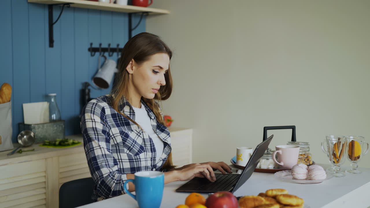 Mujer trabajando con el portátil en la cocina durante el desayuno
