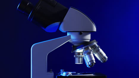 Video-of-close-up-of-laboratory-microscope-with-copy-space-on-blue-background