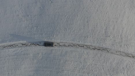 A-black-suv-slowly-passing-through-a-snowy-hillside