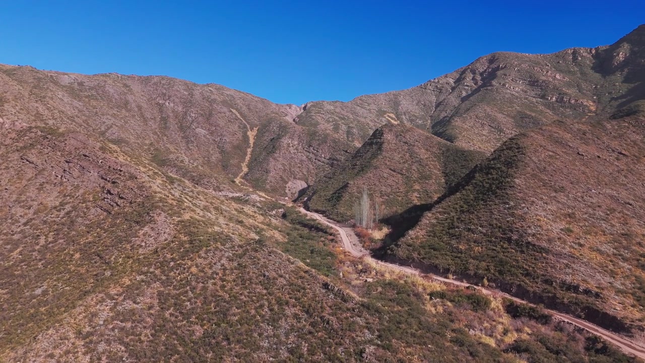 Ampia ripresa drone che rivela la cima di una collina in mezzo a montagne erbose in Argentina.