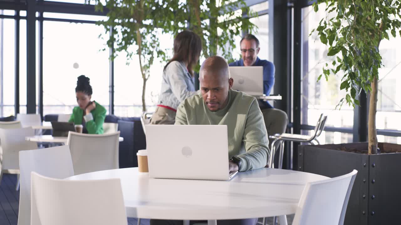 Uomo afroamericano accigliato dopo che una donna indiana asiatica mostra uno smartphone in un moderno caffè coworking