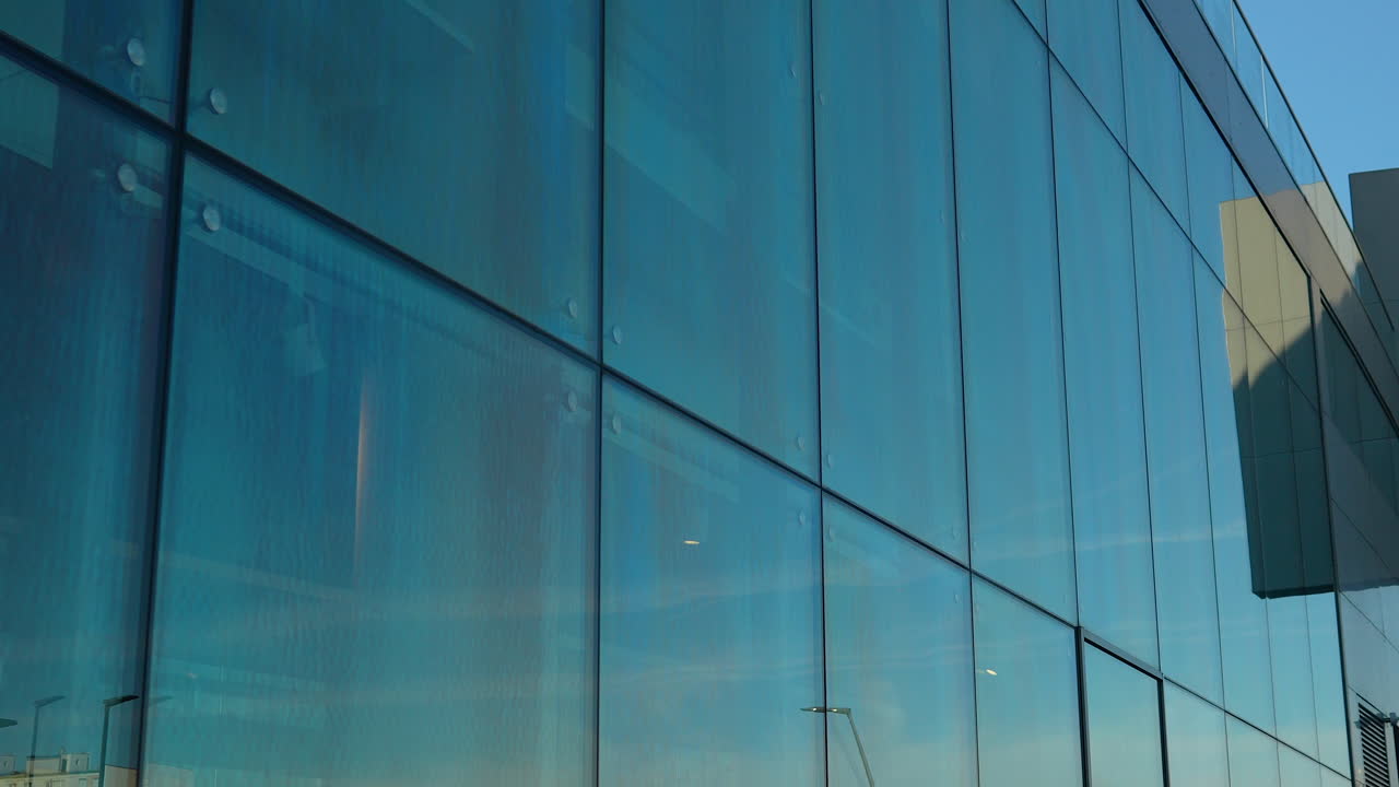 Blue sky reflected in the large glass panels of a modern building's exterior wall