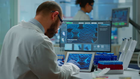 biochemist checking manifestations of virus looking in tablet